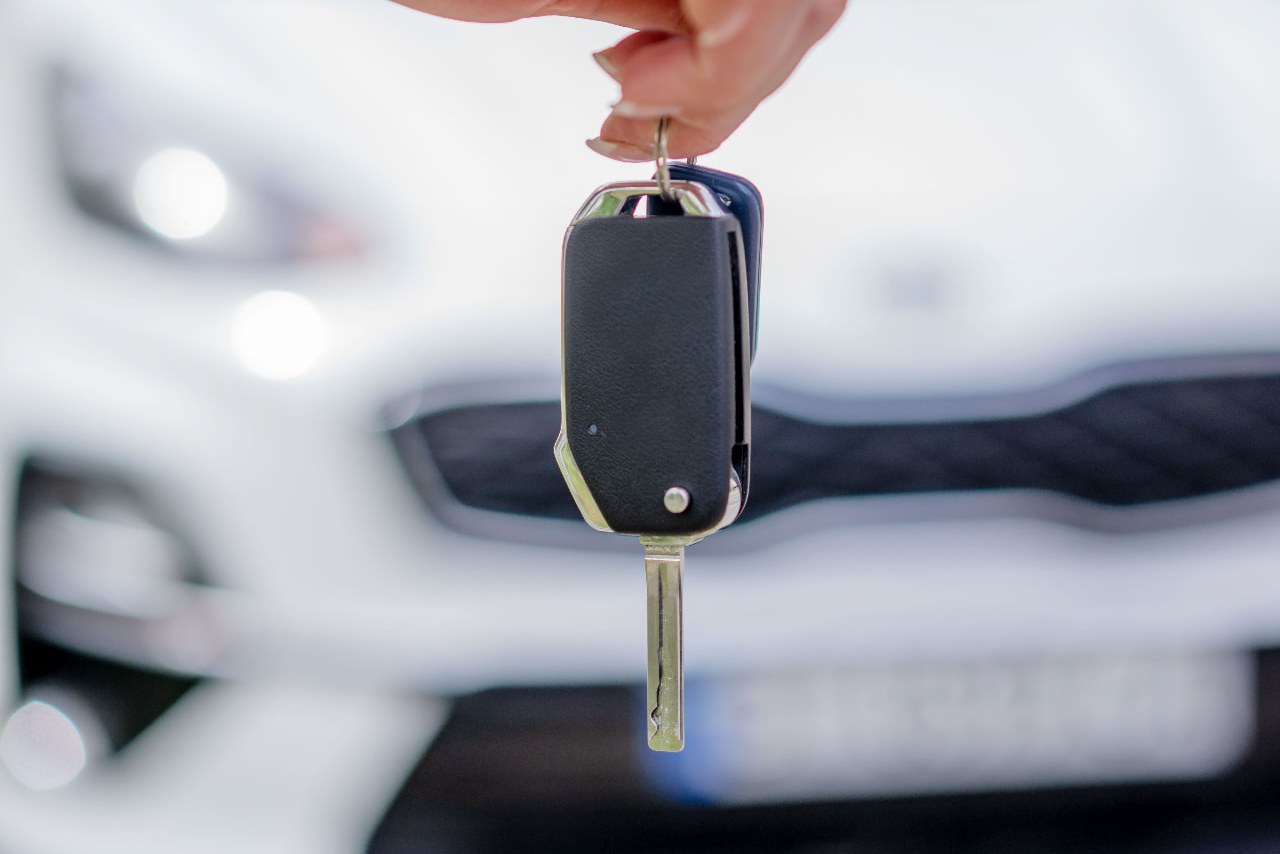 Hand holding a set of car keys in front of a hire car